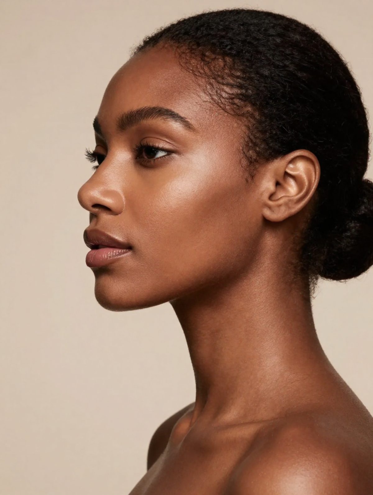 Portrait de profil, peau nue, lumière naturelle sur fond ivoire.
