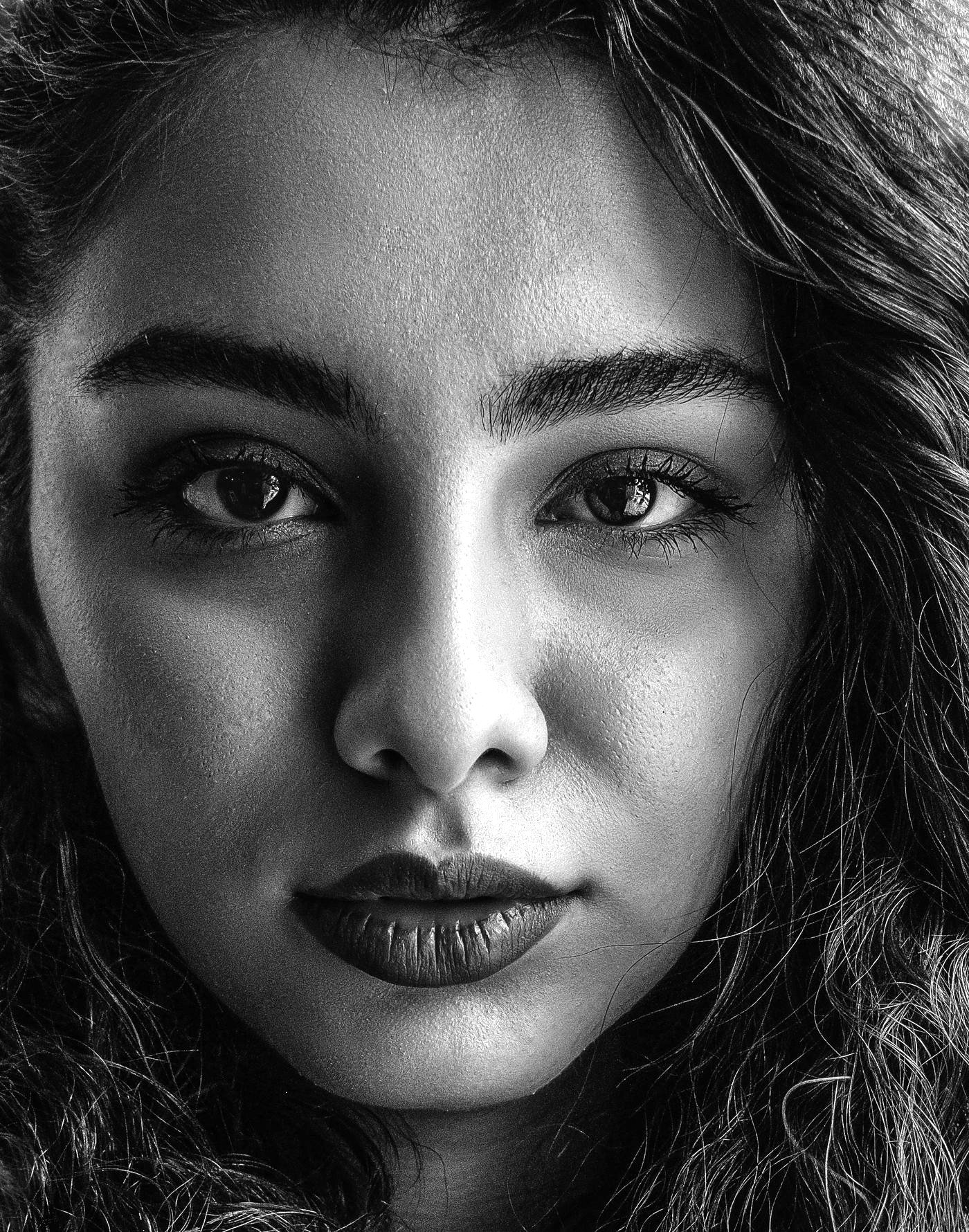 Portrait rapproché d’une femme au teint mat clair, cheveux bruns, lumière chaude.